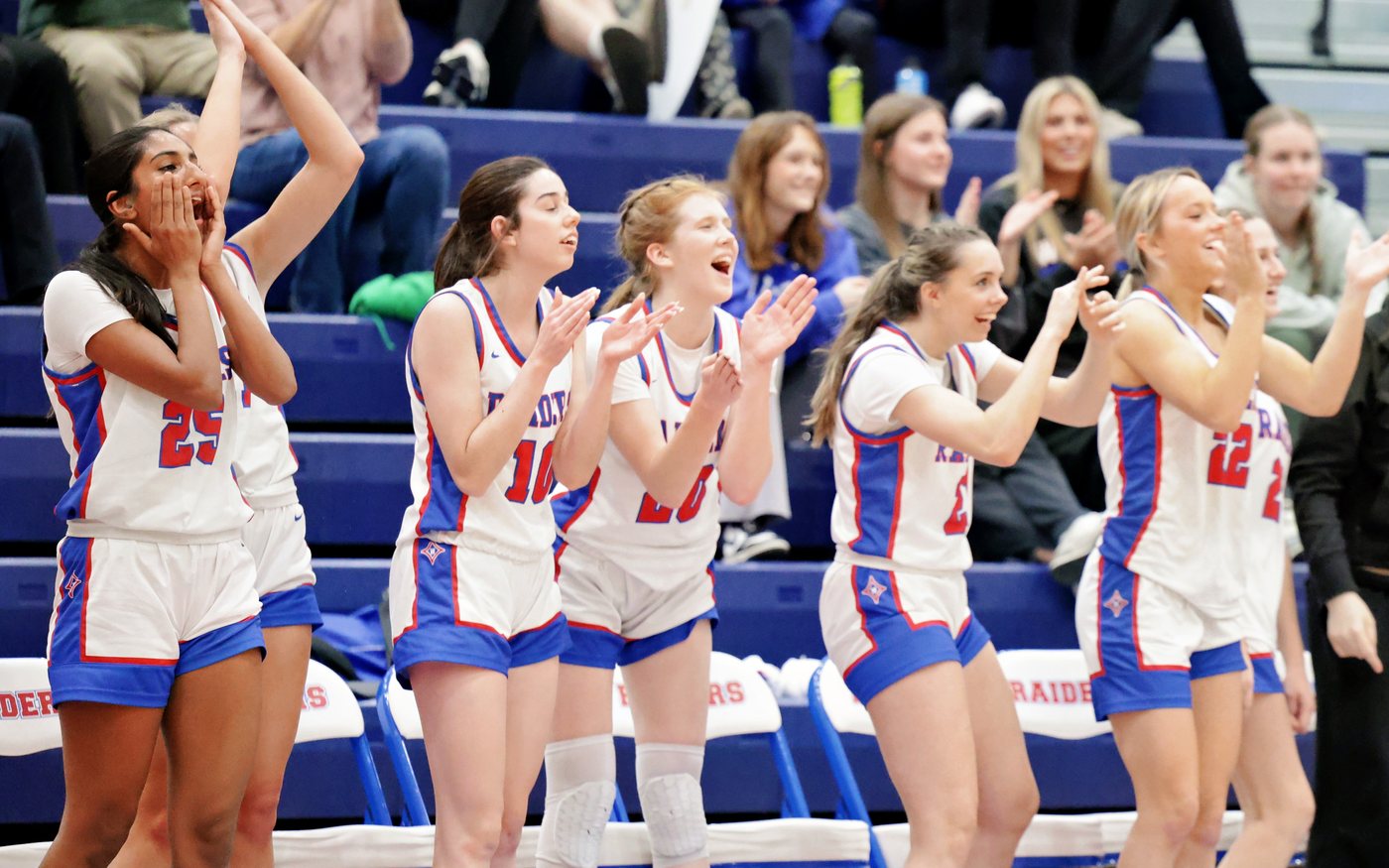 The Walton Raiders bench on its feet celebrating, with a full crowd in the stands behind them